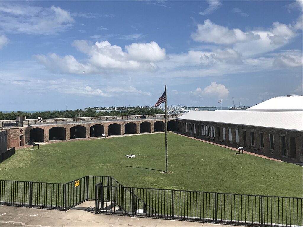 An expansive grassy courtyard enclosed by the arched brick walls of a fort.