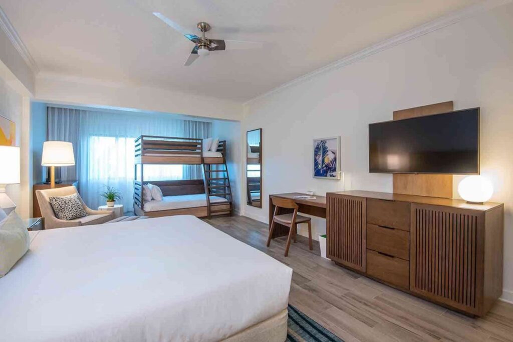A spacious resort room configured with a king bed, wooden bunk beds, and modern furnishings.