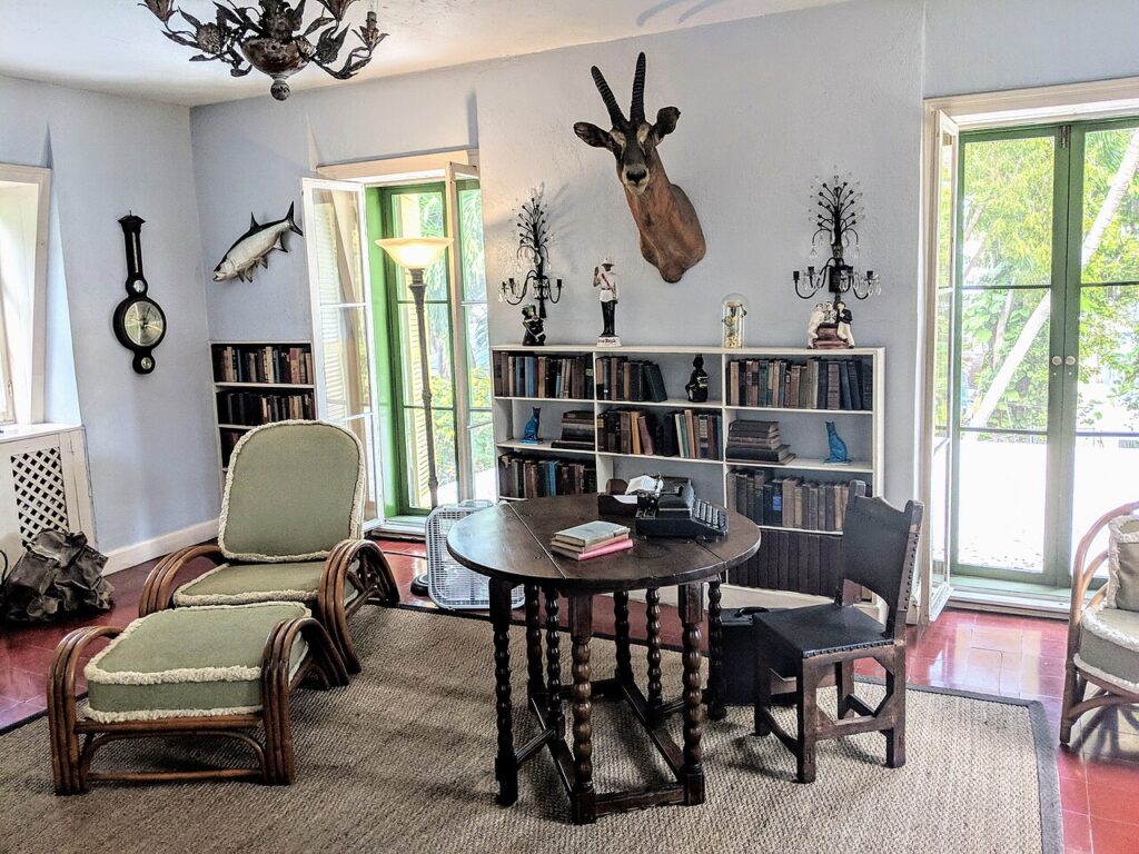 A cozy den inside the Hemingway Home with a wooden table and rattan chairs.