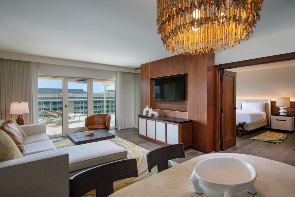 A spacious suite at JW Marriott Marco Island with a living area, a large woven chandelier, and a separate bedroom.