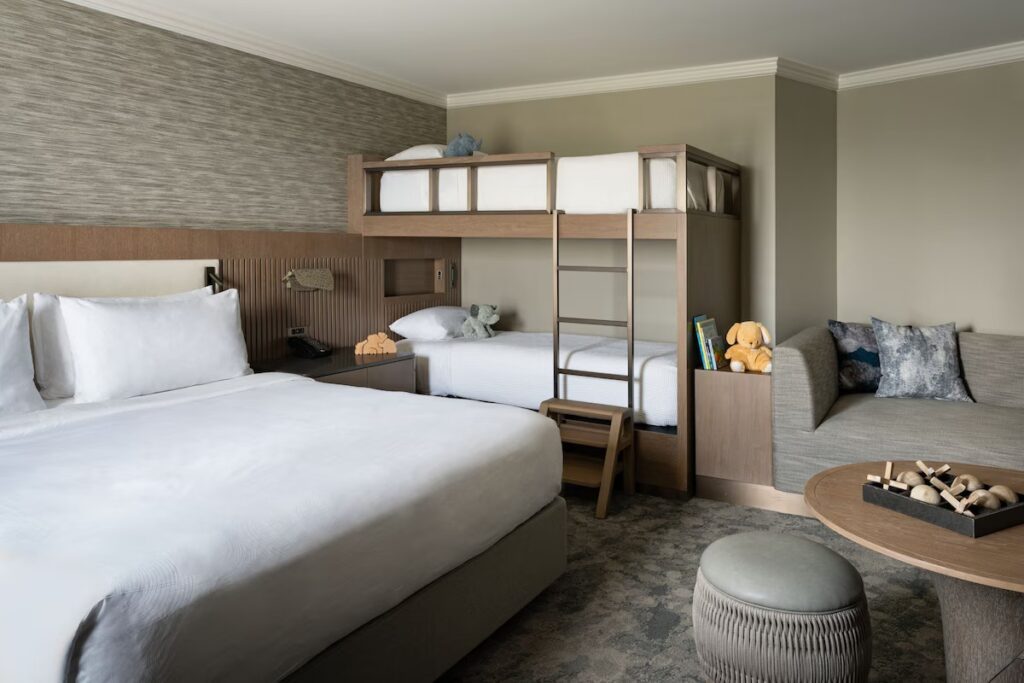 A modern family hotel room equipped with a king bed and built-in wooden bunk beds.