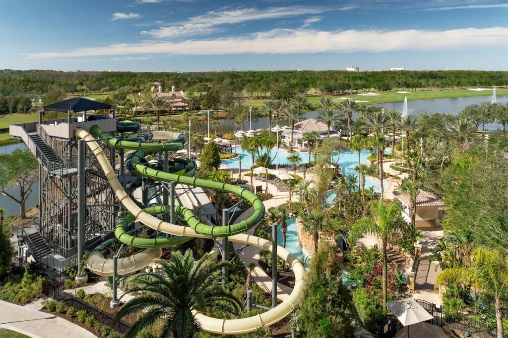 An aerial view of a large water park complex featuring tall winding slides and tropical pools.