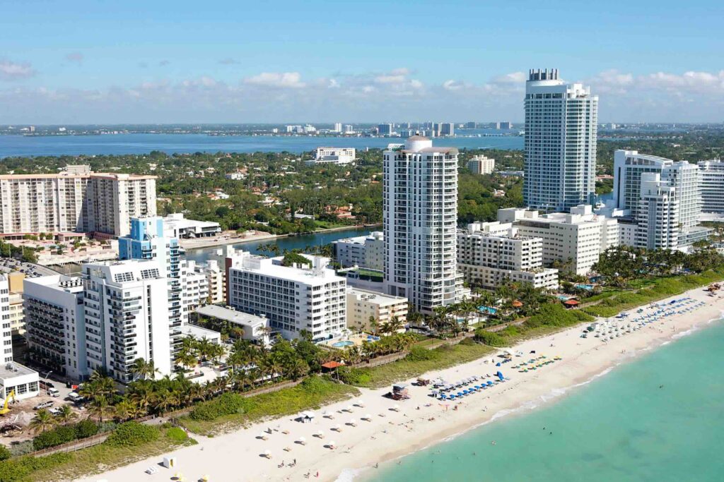 A sunny aerial view of the Miami skyline and beach, showing peak season activity.