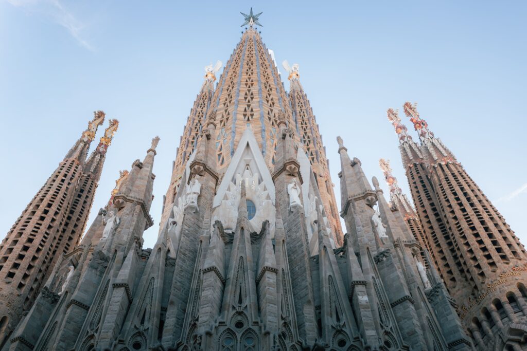 A low-angle view looking up at the towering, intricately carved stone spires of the Sagrada Família basilica.