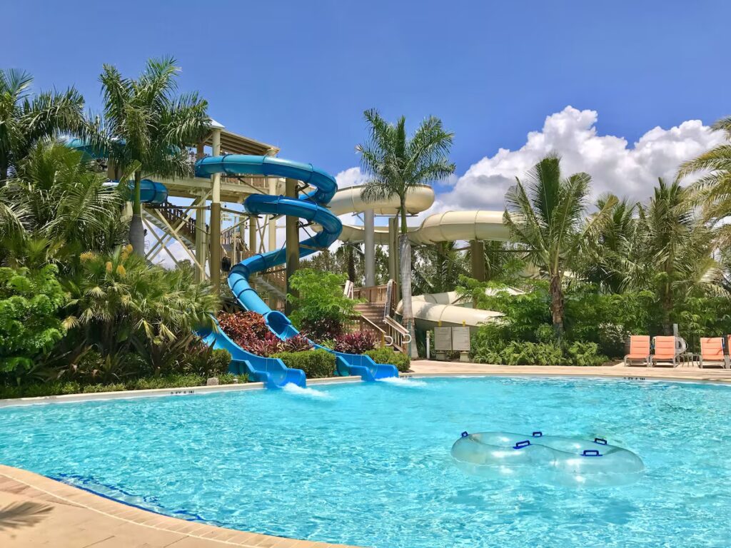A winding blue waterslide ending in a clear pool with an inflatable float at one of the best family resorts in florida.