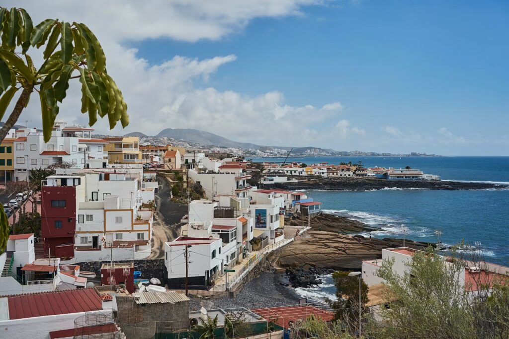 White houses along a dark volcanic rocky coast in the Canary Islands.