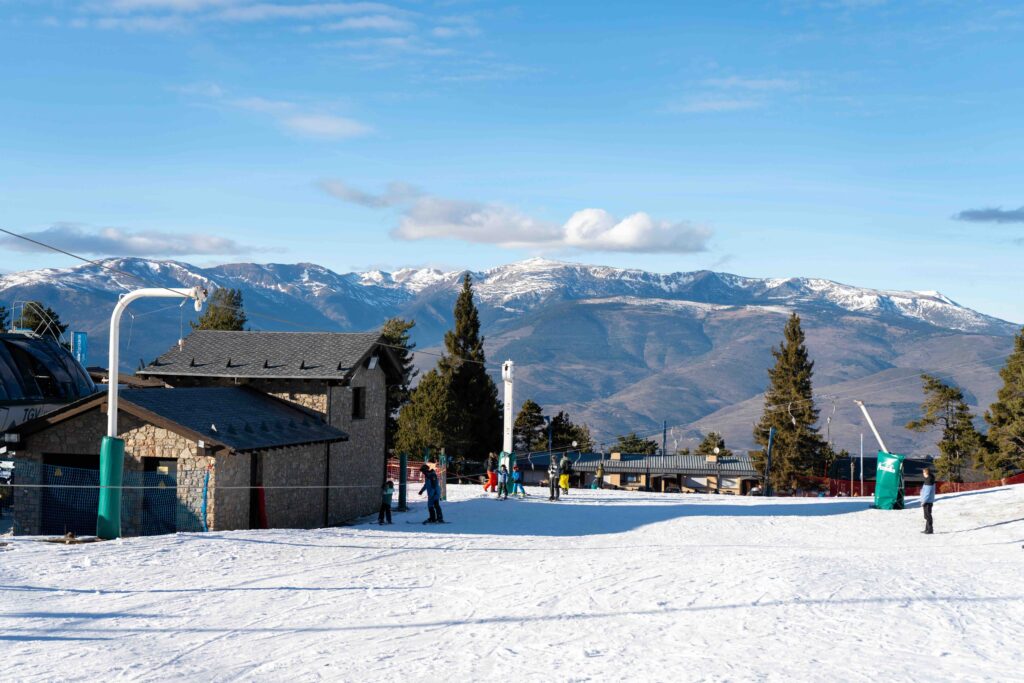 Skiers at a snowy mountain resort with stone buildings and clear blue skies.