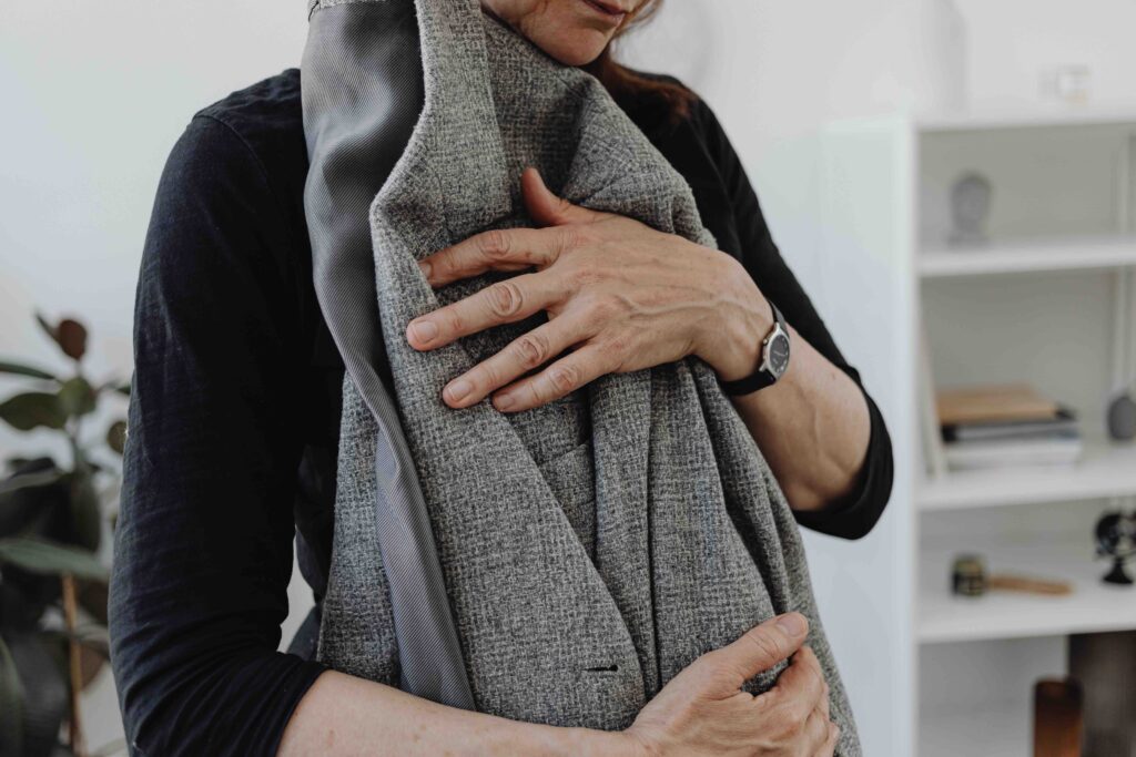 Close-up of hands folding a gray suit jacket inside-out to protect the lapels and shoulder lining during travel.