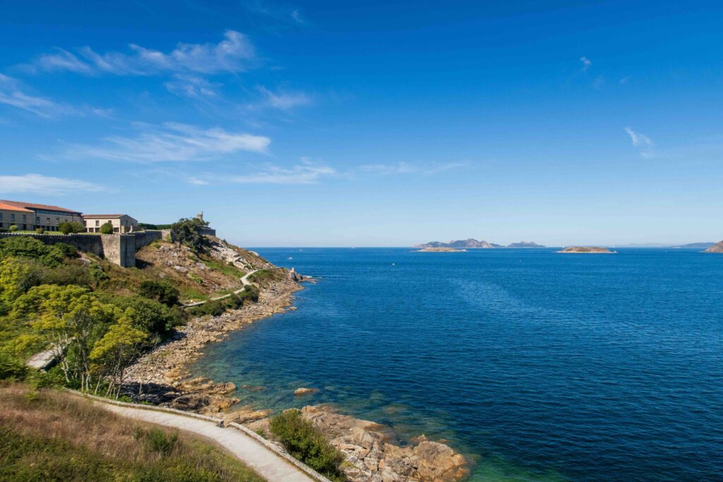 A coastal trail along rocky green cliffs overlooking the clear blue sea.