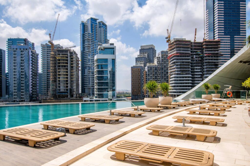 Rooftop swimming pool against city skyline during warm Dubai travel season.