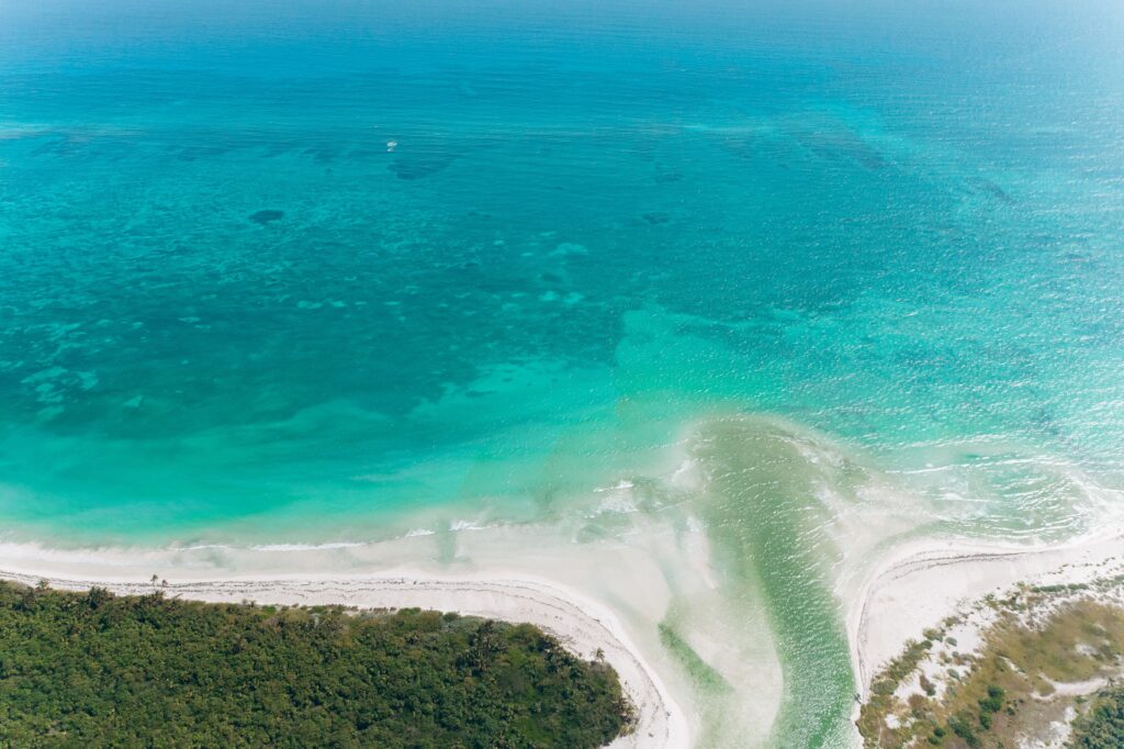 Aerial view of white sand beach and turquoise water at remote island beach camps.