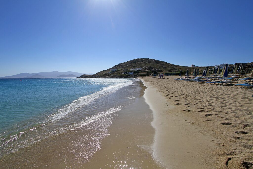 Clear turquoise water washing onto a golden sandy shore at popular Greece beaches.