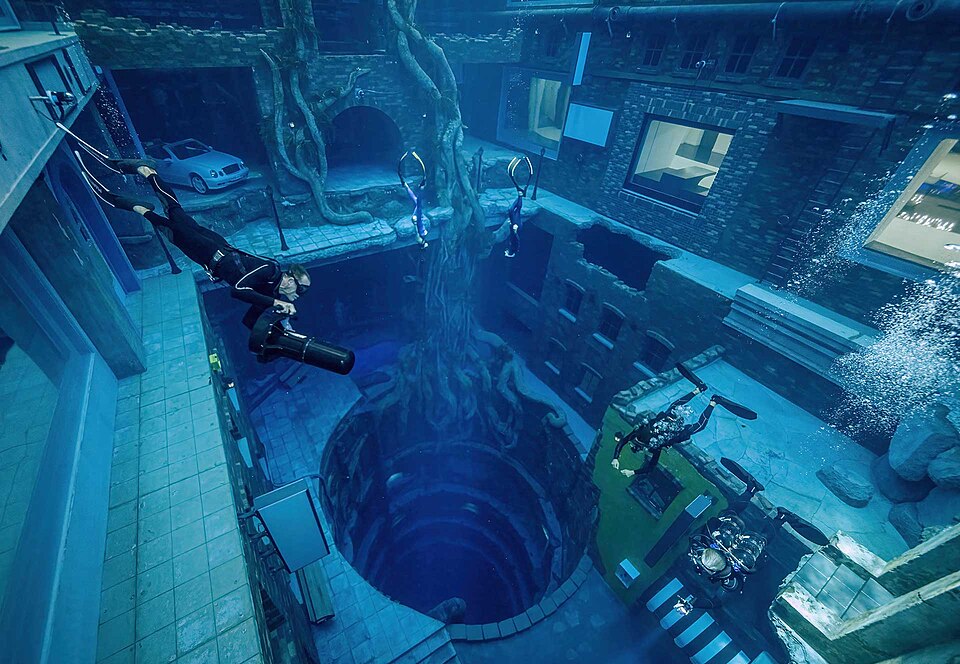 Scuba divers exploring sunken underwater city inside Deep Dive Dubai pool, thrilling answer for what to do in dubai.