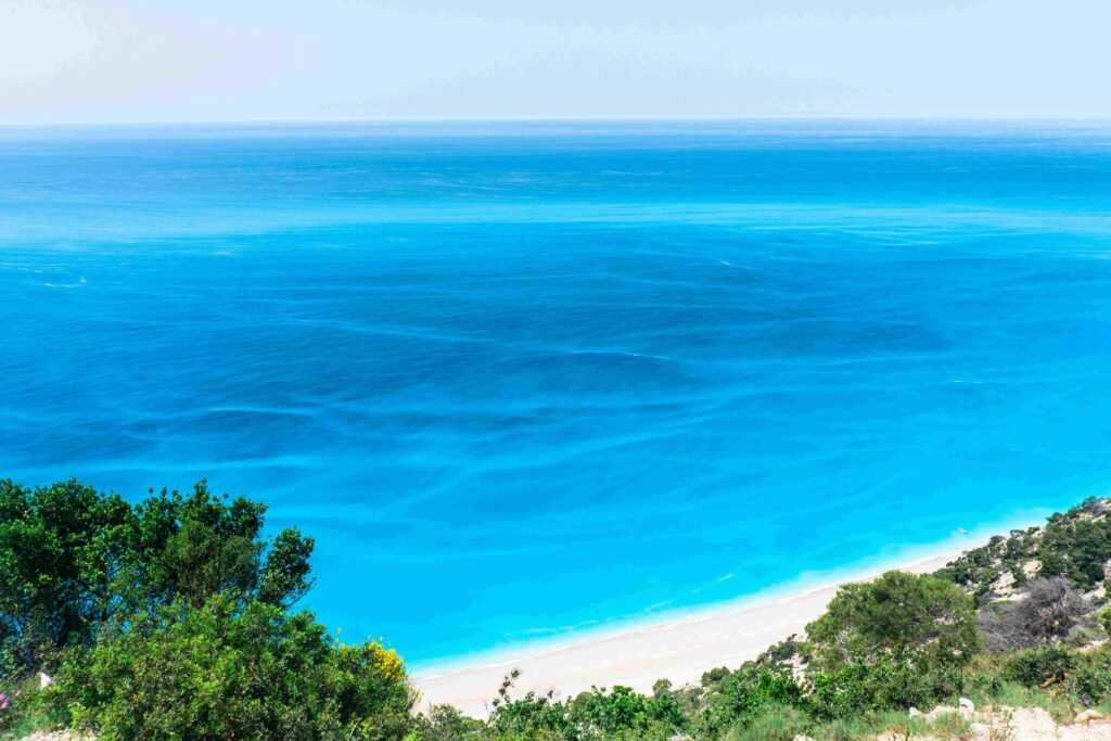 A long stretch of clear sea backed by steep white bluffs on Greece's coastline.