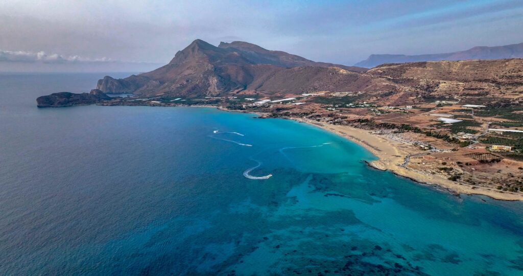 Broad turquoise coastline stretching along rocky hills at top beaches in Greece.