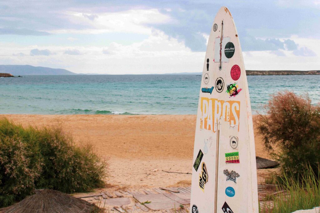 Surfboard placed on a golden sandy shoreline at best Greece beaches.