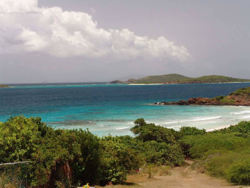 Elevated view of tropical green hills framing turquoise bay at caribbean for camping.
