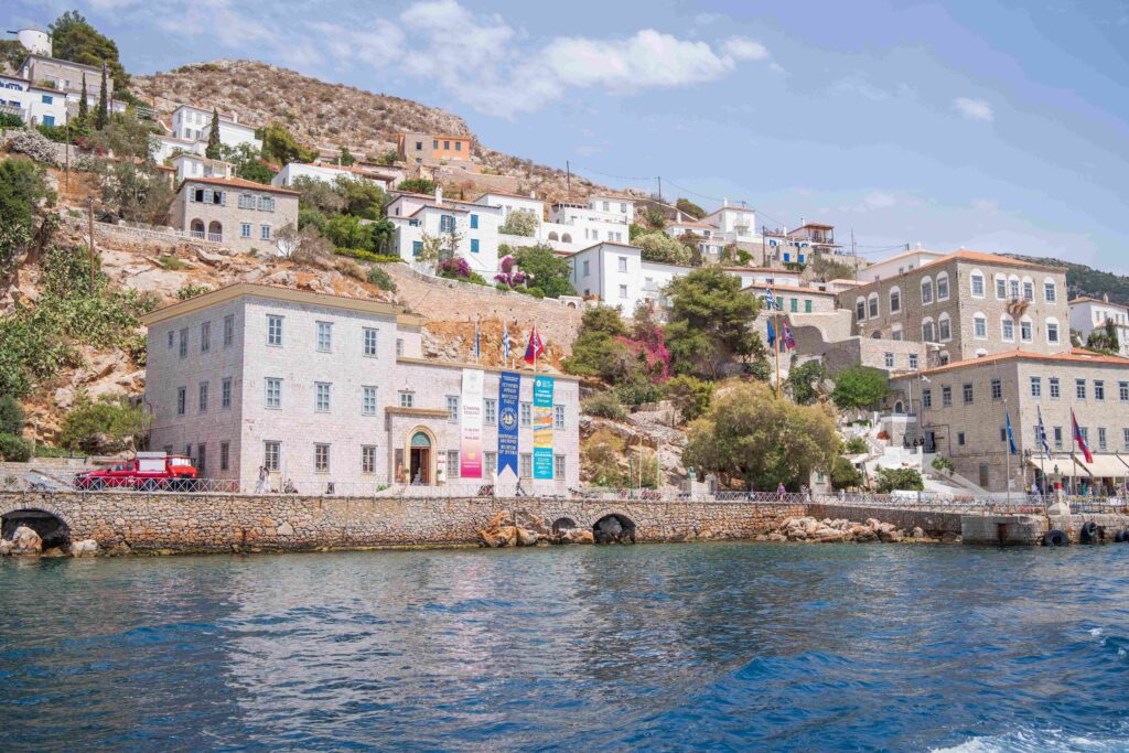 Waterfront stone buildings in Hydra town representing peaceful Greek islands.