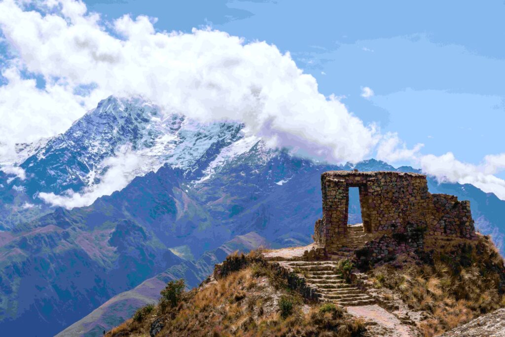 Stone Incan portal overlooking dramatic glacier peak along cloud forest trail.