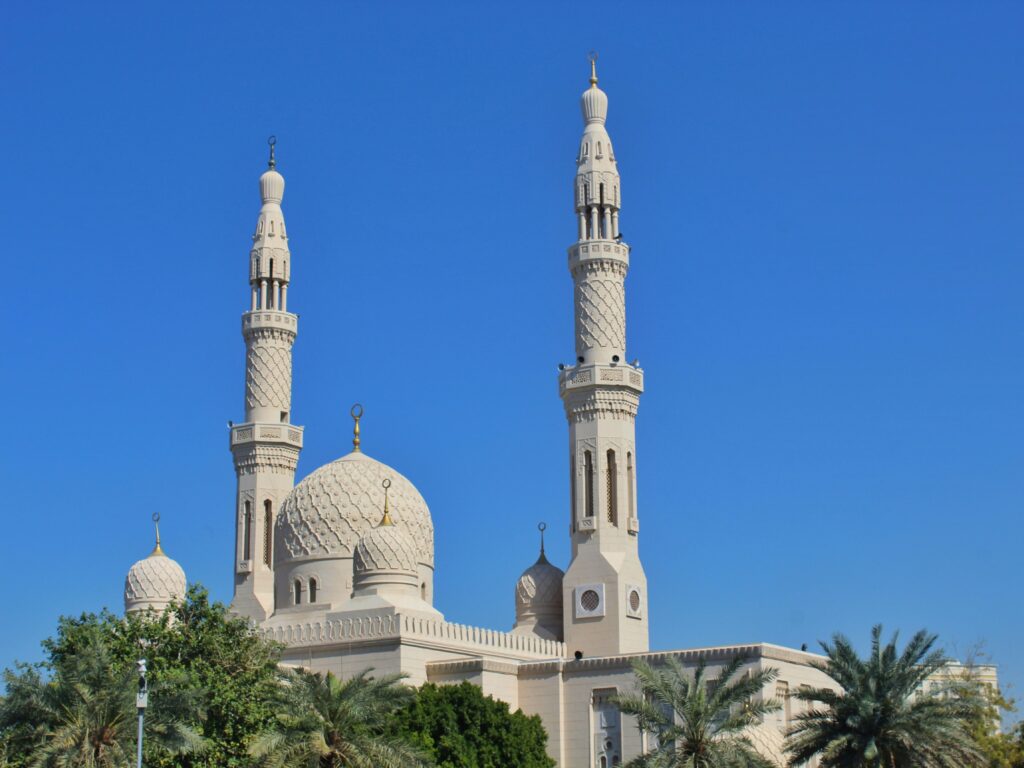 Elegant white minarets and dome of Jumeirah Mosque against a blue sky, key stop on any Dubai city tour.