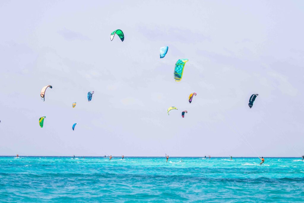 Colorful kitesurfers gliding across blue sea waters near Kite Beach, exciting choice in Dubai attractions.