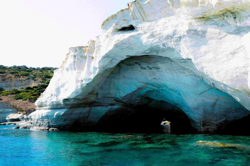 Natural sea arch and white rock formations around clear water at top Greece beaches.