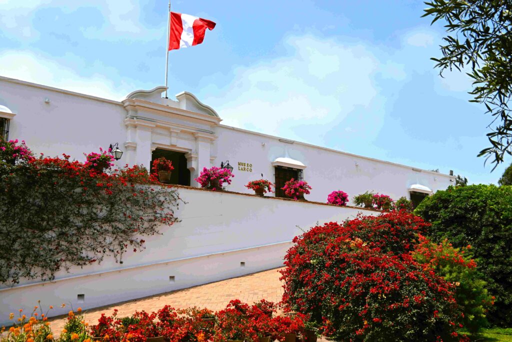White facade of Larco Museum surrounded by flowers for Lima Peru travel guide.