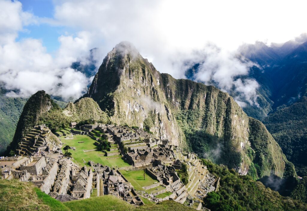 Panoramic view of ancient stone citadel surrounded by mist covered peaks for what to do in Peru.