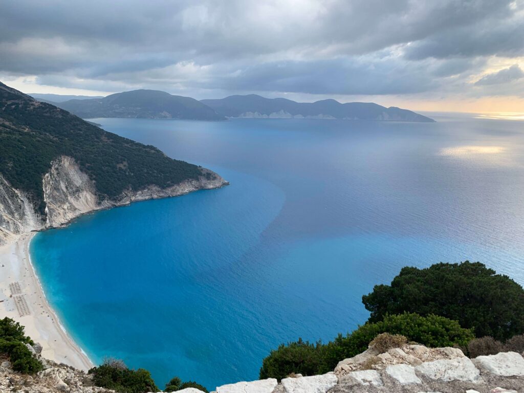 Sweeping bay of turquoise sea framed by green hills along Greek shores.