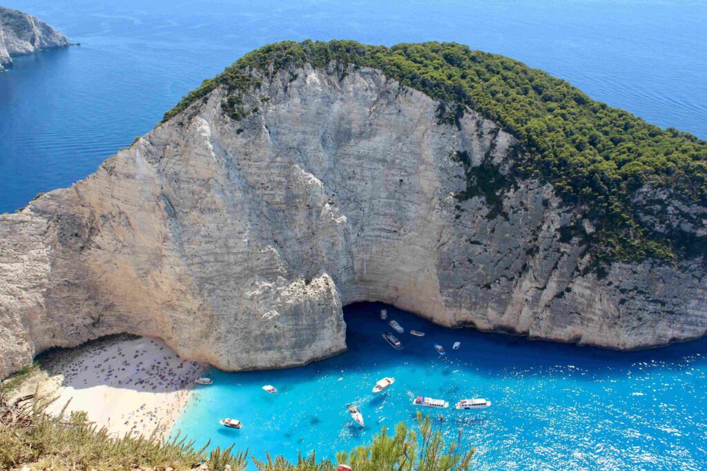 Steep limestone cliffs encircling shipwreck cove on famous Greece beaches.