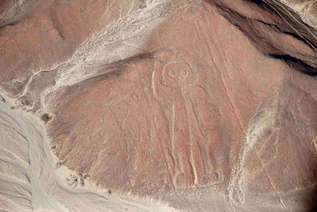 Aerial view of pre-Incan astronaut geoglyph etched on dry desert plateau in Peru.
