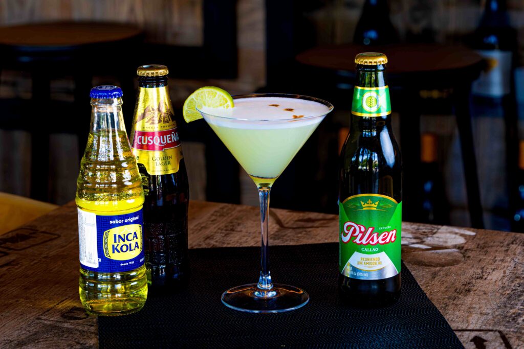 Classic Pisco Sour cocktail served with Inca Kola bottle, one of famous Peruvian drinks.