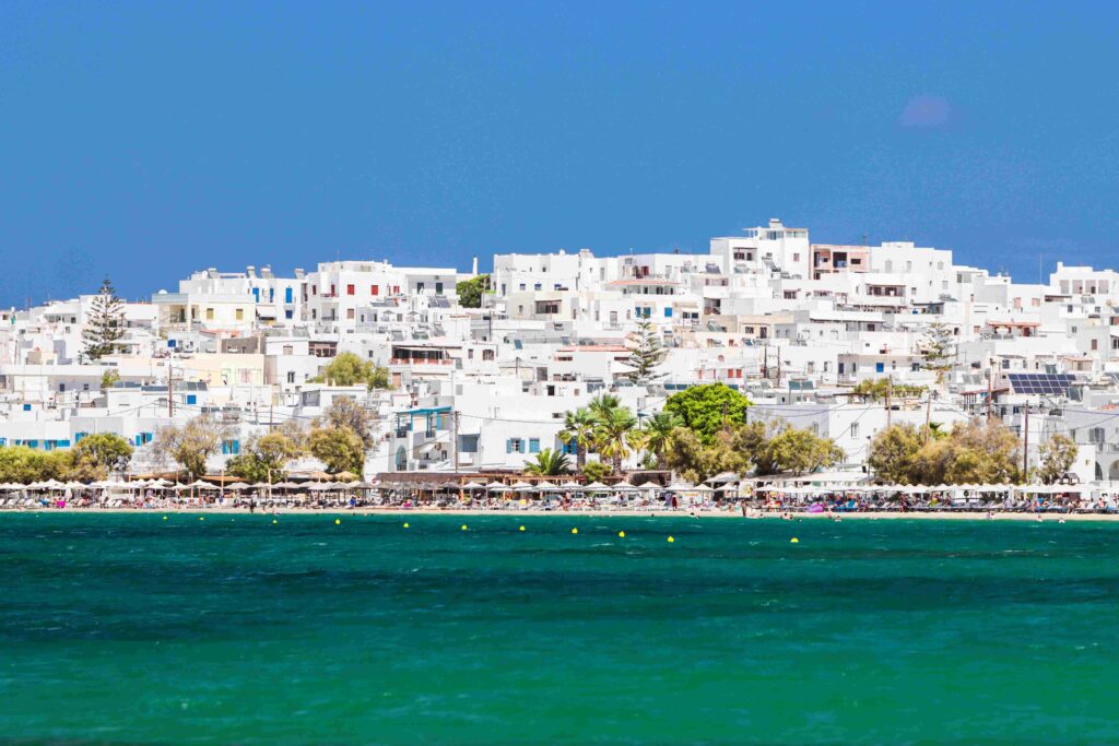White village overlooking turquoise bay and sandy coast at Greece coastal spots.