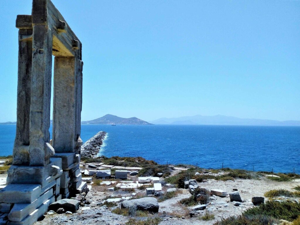 Ancient stone ruins overlooking blue sea with reference to the number of Greek islands.