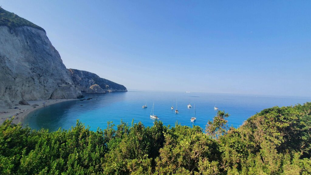Deep blue sea backed by massive concave cliffs at top Greek beaches.