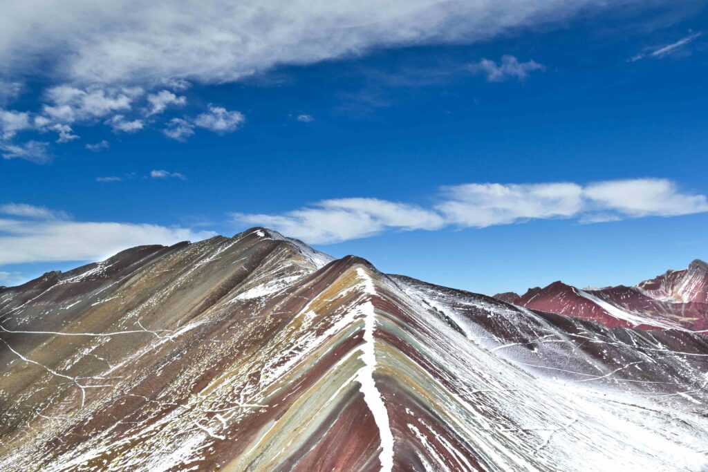 Snow capped ridge of Rainbow Mountain under a blue sky during ideal Peru travel season.