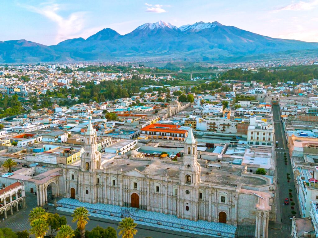 Aerial view of white sillar cathedral plaza framed by volcanoes in Arequipa, Peru.