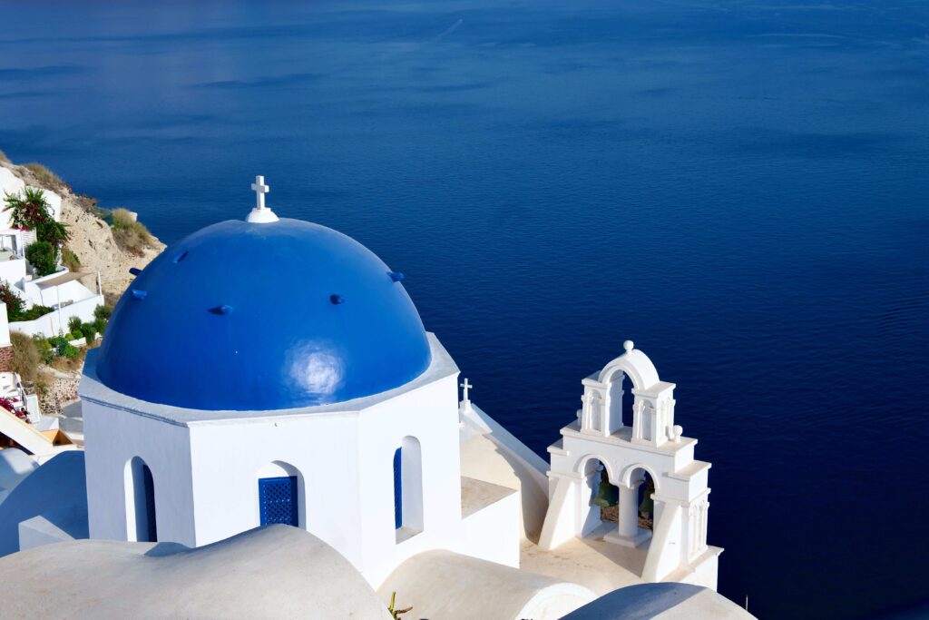 Iconic blue-domed church looking over the Aegean Sea in Santorini among top Greek island spots.