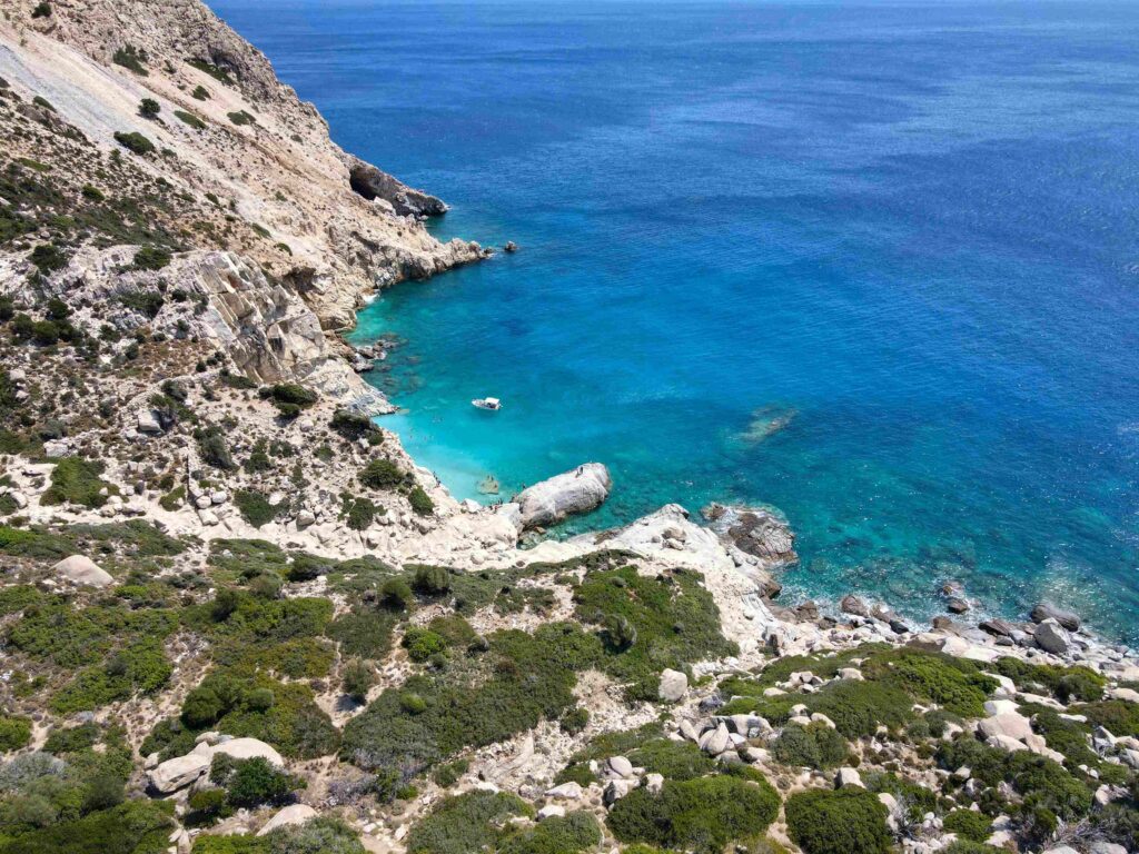 Turquoise water surrounding granite boulders and steep cliffs on hidden Greece beaches.
