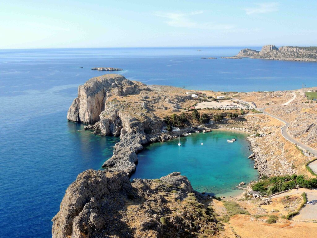 Enclosed circular cove with clear blue water seen from above in scenic Greece beaches.