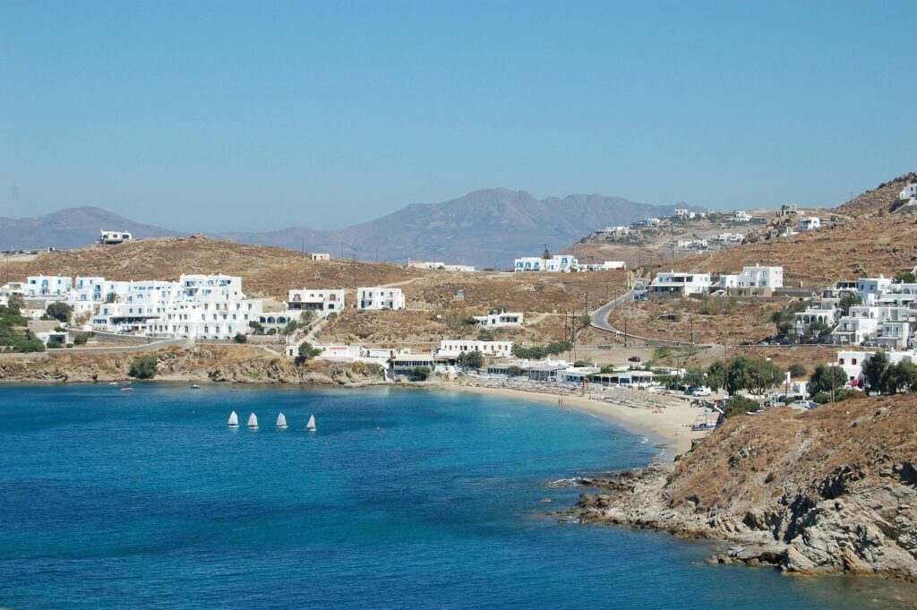 Deep blue bay surrounded by coastal hills and white buildings on Greece resort beaches.