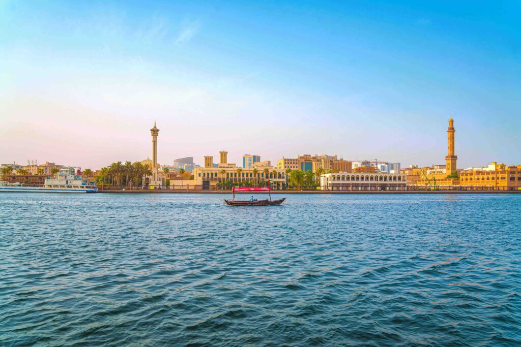 Wooden abra boats floating past historic waterfront buildings along Dubai Creek, a must see in Dubai.