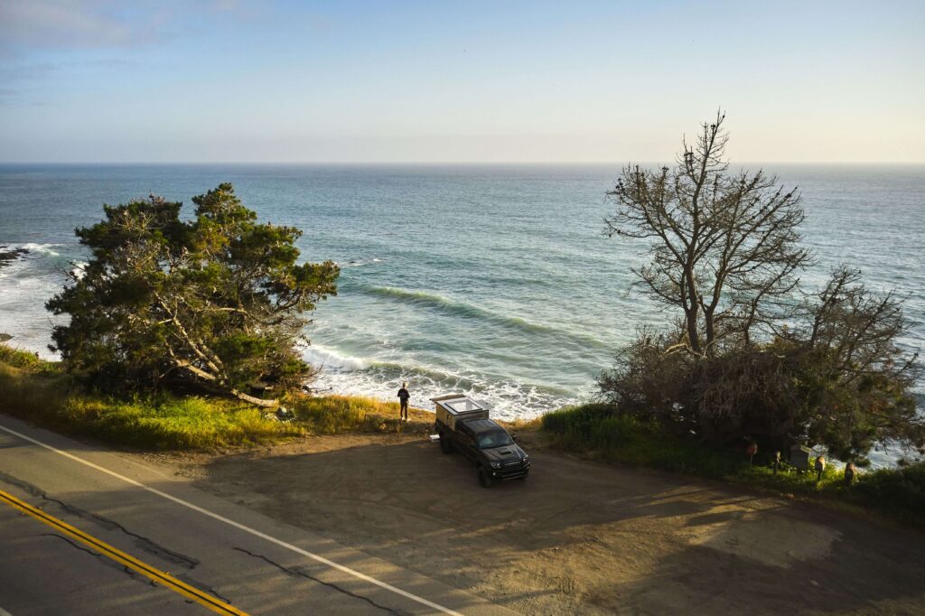 Truck camper parked on cliffside overlooking sea at ocean view campgrounds.