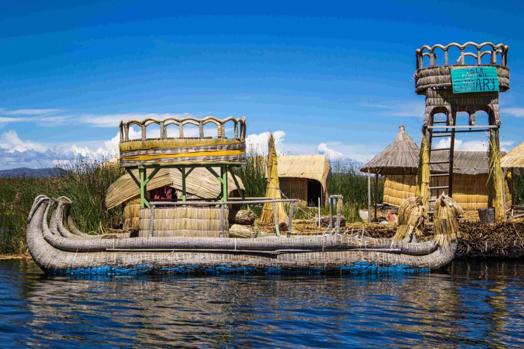 Woven totora reed boat and thatched floating houses on Lake Titicaca, Peru.