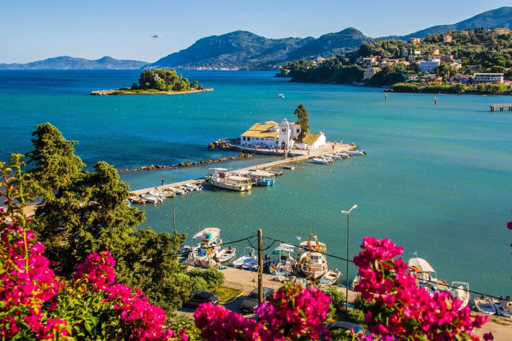 Historic monastery in a turquoise bay surrounded by greenery on inhabited Greek islands.