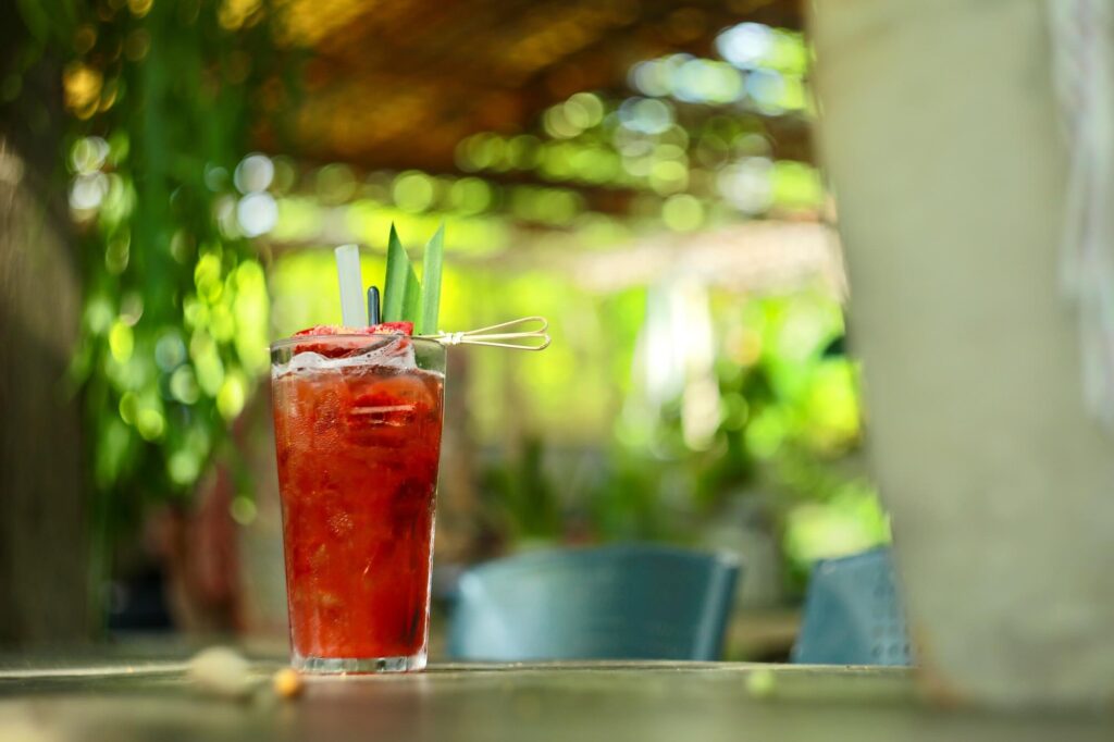 A bright red Bloody Mary cocktail in a tall glass garnished with a skewer on an outdoor table. Source: Pexels